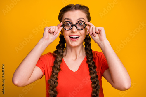 Photo of funny pretty student lady clever diligent pupil hold spectacles hands open mouth eyesight correction wear freak specs casual red t-shirt isolated bright yellow color background