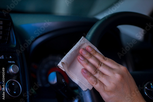 Asian women spry soap and clean car steering wheel with napkin, concept for  Coronavirus, Covit-19 prevention and disinfection. photo