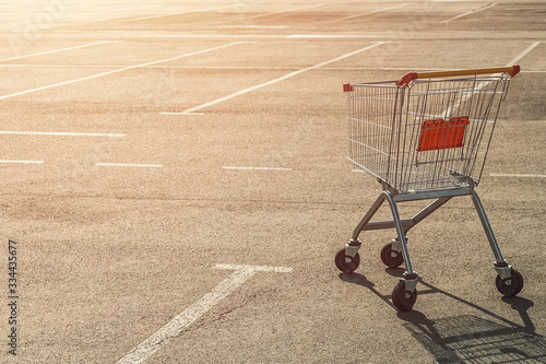Cuadro en lienzo Single abandoned empty shopping trolley in an empty parking lot near a supermarket in the absence of people at sunset