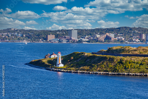 Entrance to Harbor in Halifax, Nova Scotia marked by an orange and white lighthouse on a point of green land
