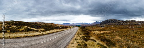 Road between fields and mountains on a cloudy day in Scotland