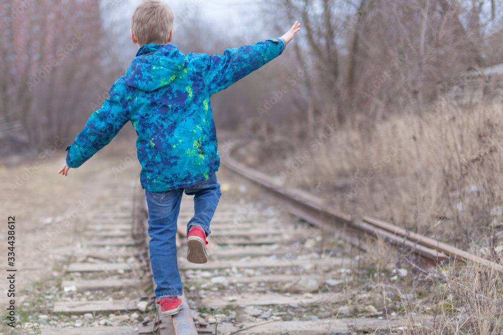 Child balancing goes on railway rails. Homeless child walks on the ...
