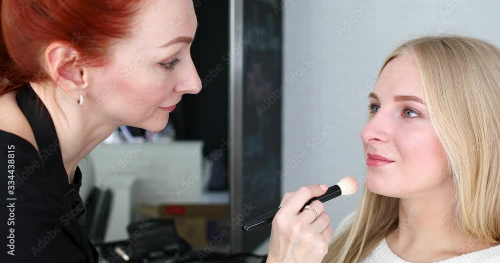 Red haired beautician artist doing makeup for blonde female Red haired beautician artist doing makeup for blonde female