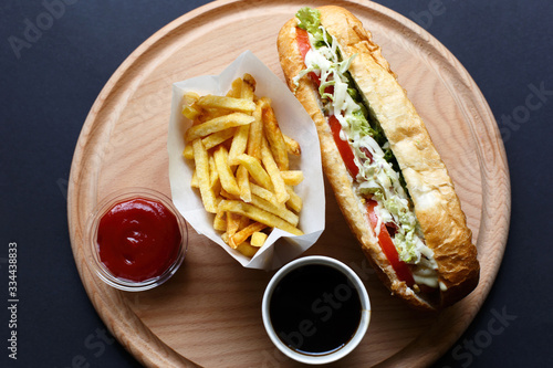 Hot Dogs with French fries and ketchup on wooden plate. photo