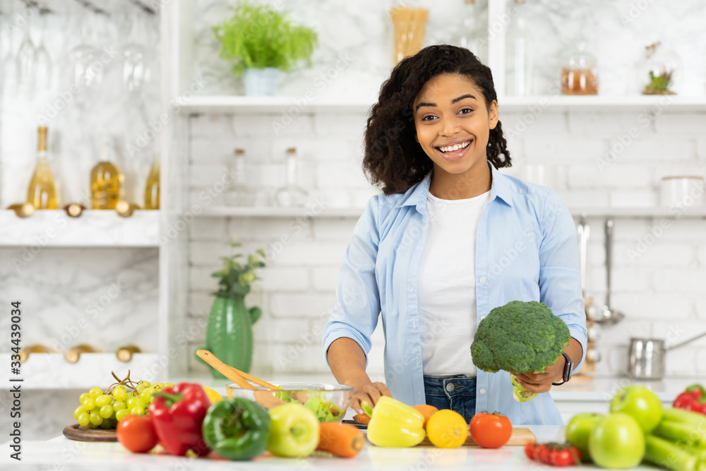 Happy young afro girl preparing vegetable salad for family Happy young afro girl preparing vegetable salad for family