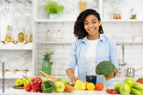 Happy young afro girl preparing vegetable salad for family