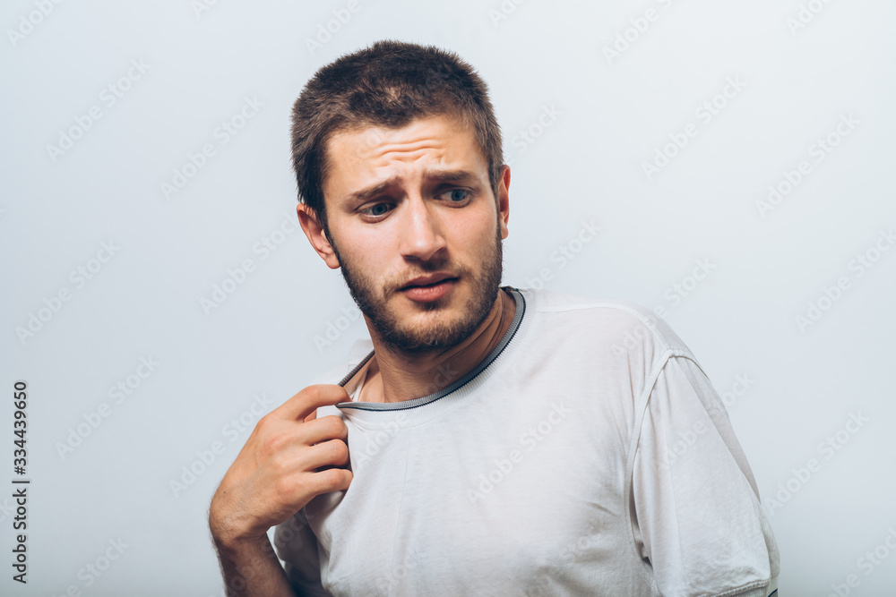 Closeup portrait of young man opening shirt to vent,it's hot. Negative emotion, facial expression, feeling Closeup portrait of young man opening shirt to vent,it's hot. Negative emotion, facial expression, feeling