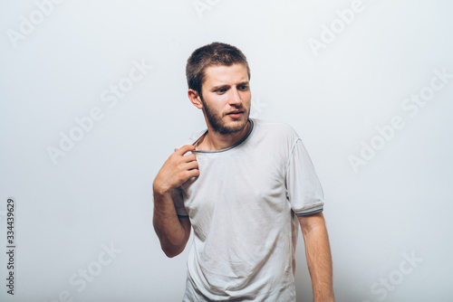 Closeup portrait of young man opening shirt to vent,it&#39;s hot. Negative emotion, facial expression, feeling