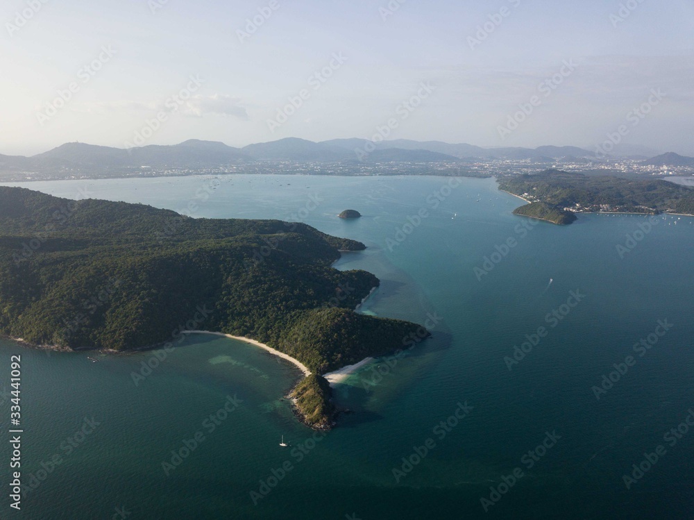 aerial view of the island, shoot from sky on sunset time, mountain, small free beach, behind Phuket city and mountains.