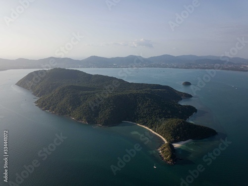 aerial view of the island on sunset time, mountain, small free beach, behind Phuket city and mountains.