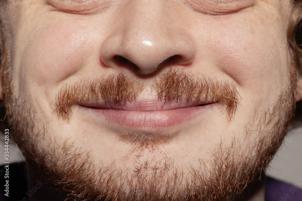 Smiling. Close up of face of beautiful caucasian young man with redhair beard, focus on mouth. Human emotions, facial expression, cosmetology, body and skin care concept. Well kept skin. Wellbeing. Smiling. Close up of face of beautiful caucasian young man with redhair beard, focus on mouth. Human emotions, facial expression, cosmetology, body and skin care concept. Well kept skin. Wellbeing.