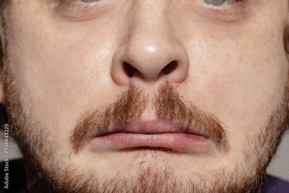 Sad, upset. Close up of face of beautiful caucasian young man with redhair beard, focus on mouth. Human emotions, facial expression, cosmetology, body and skin care concept. Well kept skin. Wellbeing. Sad, upset. Close up of face of beautiful caucasian young man with redhair beard, focus on mouth. Human emotions, facial expression, cosmetology, body and skin care concept. Well kept skin. Wellbeing.