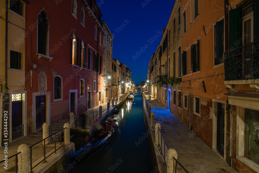 Canale illuminato di sera vicino canal grande, con case colorate a Venezia, Italia