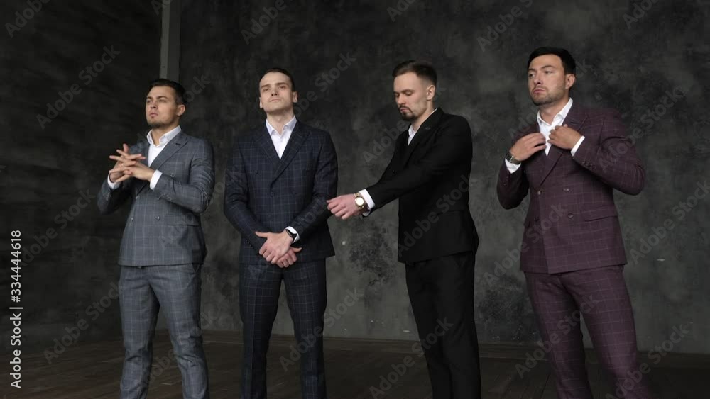 Four confident serious handsome men in business suit posing standing in modern center studio. Nice successful models 30s look at camera together indoor. Proud executive staff colleagues ready to work Four confident serious handsome men in business suit posing standing in modern center studio. Nice successful models 30s look at camera together indoor. Proud executive staff colleagues ready to work