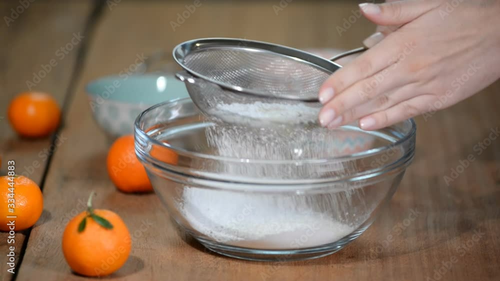 A woman sifting white flour. Home baking. A woman sifting white flour. Home baking.