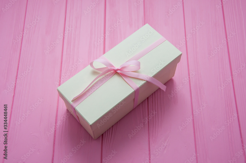White gift with pink bow. Gift or present box on wooden pink background with copy space. Pastel color. Greeting card. White luxury wedding gift. Valentines day background with gift box. Mother's Day. - obrazy, fototapety, plakaty 