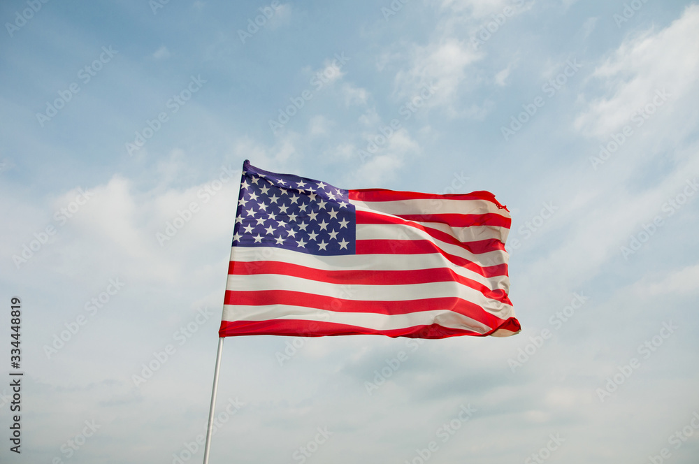 Naklejka premium Patriotic USA background with waving American flag. .American flag on the background of beautiful blue sky..The symbolic of liberty, freedom..Independence day, 4th of July..Space for text.