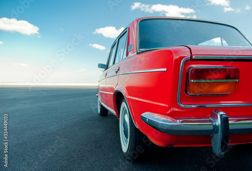 KIEV, UKRAINE-JULY 4, 2017: Red retro car VAZ-2103 "Zhiguli" parked on the road against the blue sky. Beautiful classic car on the street. Vintage auto. Close up side of ancient car. Space for text. © Ivan