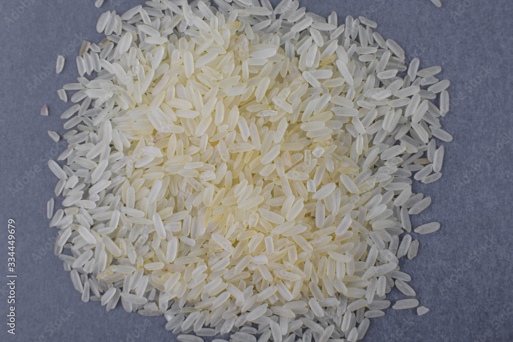 Stack of white rice grains gathered together in front on a light background