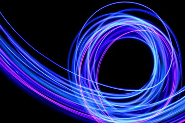 Light painting photography, long exposure photo of purple and blue streaks of vibrant color against a black background