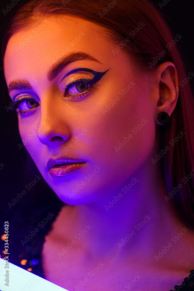 Toned portrait of beautiful woman with neon lamp on dark background Toned portrait of beautiful woman with neon lamp on dark background