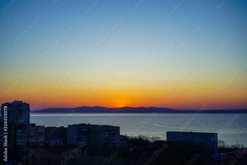 Sunset on the background of the sea and urban landscape,