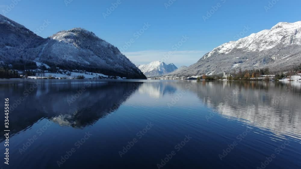 Low aerial dolly, jetty and canoe on pristine mirror-like alpine mountain lake Low aerial dolly, jetty and canoe on pristine mirror-like alpine mountain lake