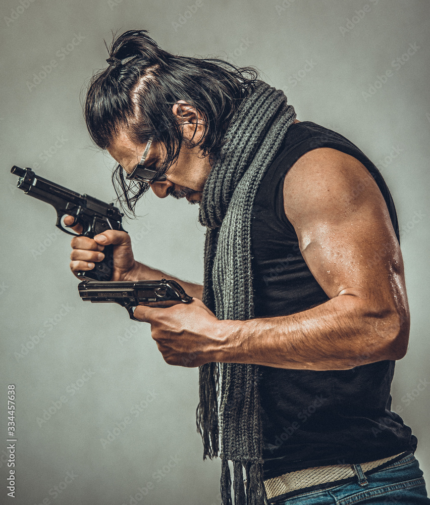 sexy muscular body model portrait of a young man holding a gun in his hands sexy muscular body model portrait of a young man holding a gun in his hands