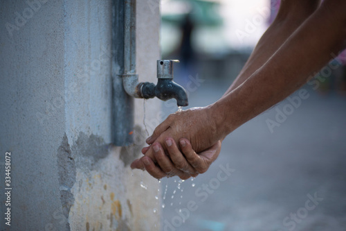 A person washing hands in tap water using sanitizer to prevent corona virus. Indian lifestyle, covid 19, pandemic 