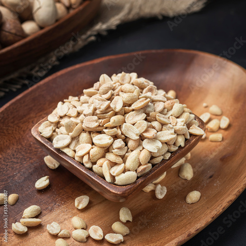 nuts on a square wooden bowl and an oval wooden tray on a dark background and burlap
