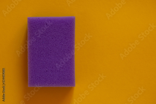 The concept of cleaning and washing. Purple sponge for cleaning on a yellow background.