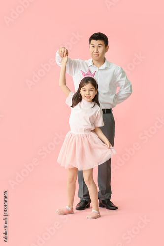 Happy Asian man and his little daughter dancing against color background © Pixel-Shot
