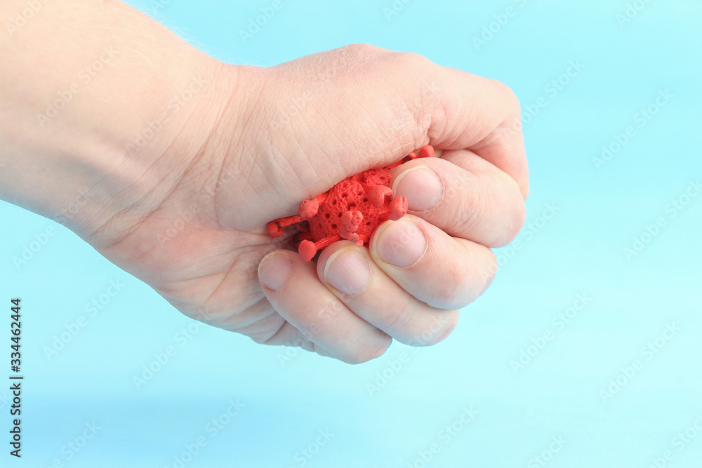 Person tries to crash red virus in his hand on the blue background. Model of virus made from plasticine and matches. Theme of health care, medical treatment and disease control. Person tries to crash red virus in his hand on the blue background. Model of virus made from plasticine and matches. Theme of health care, medical treatment and disease control.