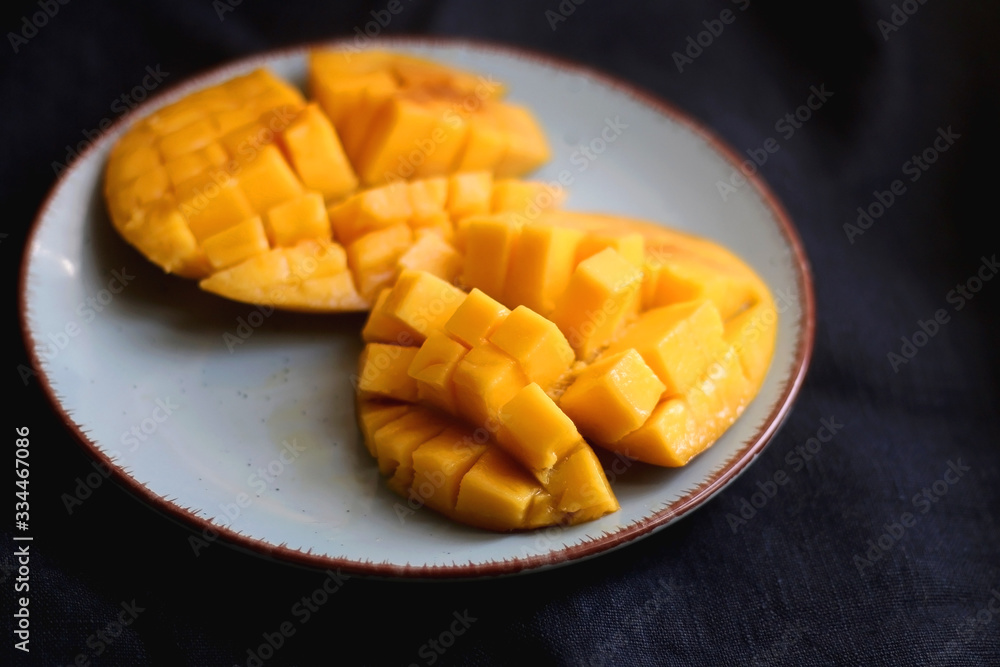 Cut mango halves on a plate. Selective focus, dark blue background. Cut mango halves on a plate. Selective focus, dark blue background.