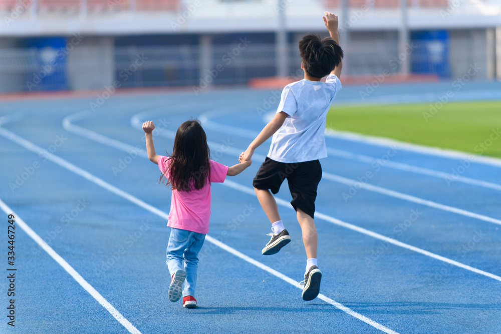 Obraz premium Young boy and girl play on a bluetrack after running