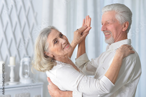 Portrait of cheerful senior couple dancing at home