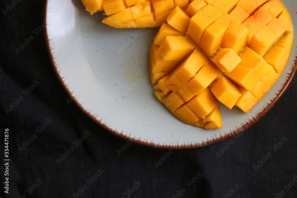 Cut mango halves on a plate. Top view, dark blue background. Cut mango halves on a plate. Top view, dark blue background.