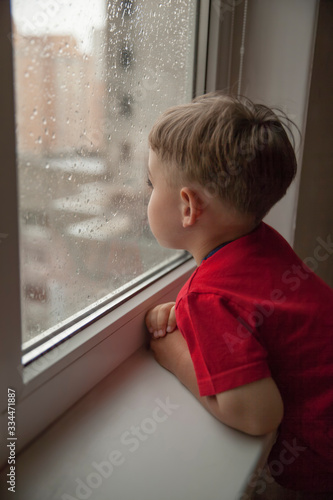 little boy watching the rain through the window. close-up	