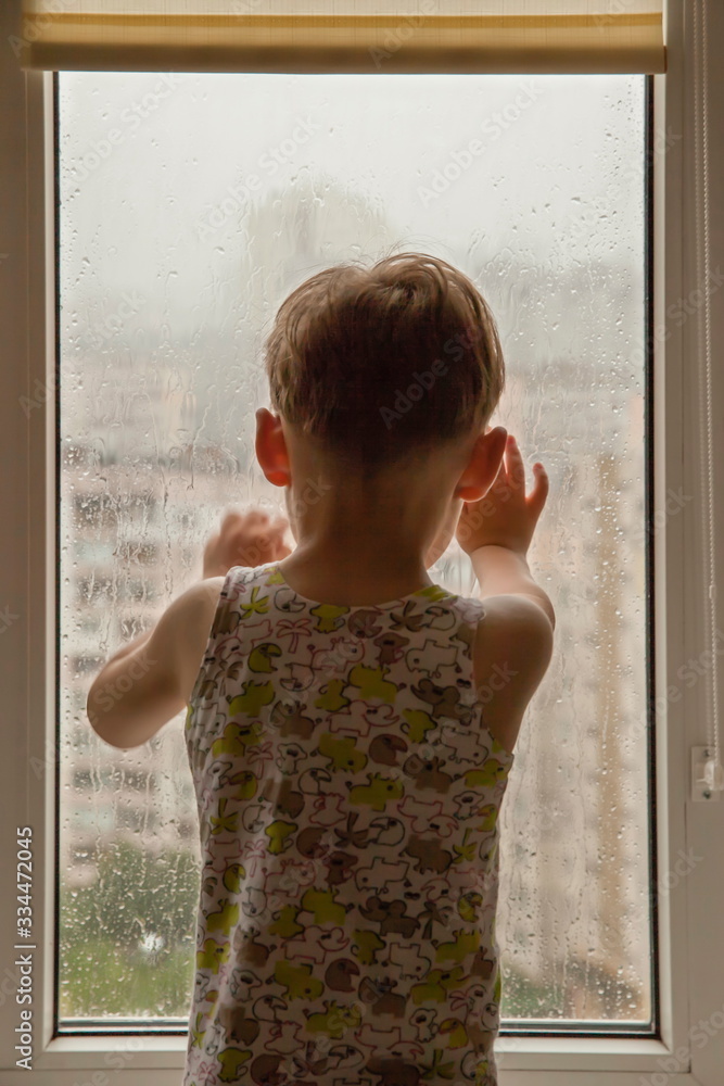 little boy watching the rain through the window. close-up little boy watching the rain through the window. close-up