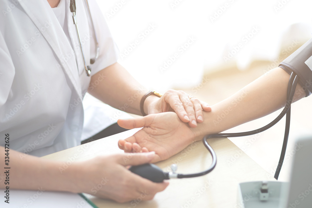 Doctor or nurse measuring checking patient pulse are examining health condition female. with a Sphygmomanometer and wrist ,Medical Check up blood pressure in clinic room hospital, Medicine health care Doctor or nurse measuring checking patient pulse are examining health condition female. with a Sphygmomanometer and wrist ,Medical Check up blood pressure in clinic room hospital, Medicine health care