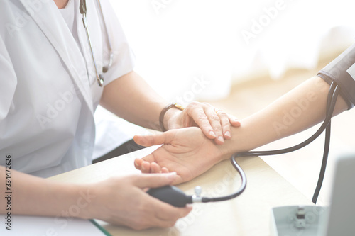 фотографія Doctor or nurse measuring checking patient pulse are examining health condition female