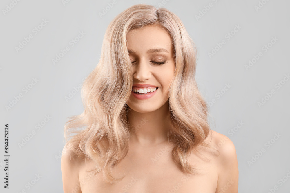 Young blonde with beautiful hair on light background Young blonde with beautiful hair on light background