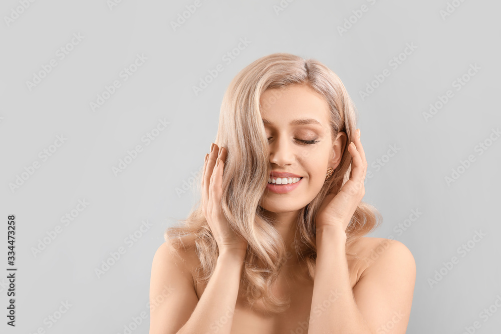 Young blonde with beautiful hair on light background Young blonde with beautiful hair on light background