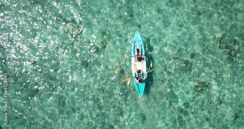 Top down aerial view shoot as couple paddle their blue white kayak in clear sea water with corals, summer time, tropical area, water touristic activity in Thailand