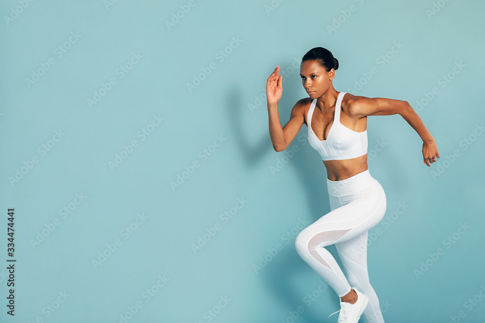 Cropped shot of fitness woman in white sportswear running over blue background Cropped shot of fitness woman in white sportswear running over blue background