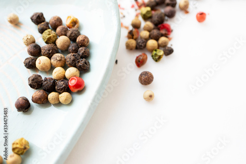 Peppercorn dry spice on saucer. Black, red, white and green pepper, close-up. Details food
