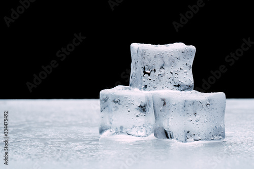 wet ice cubes with drops on a dark black background