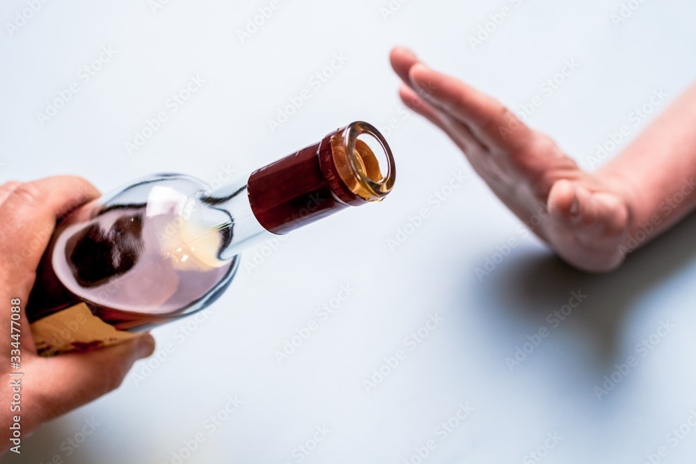 hand extended bottle of liquor on the other hand rejected. Alcoholism concept