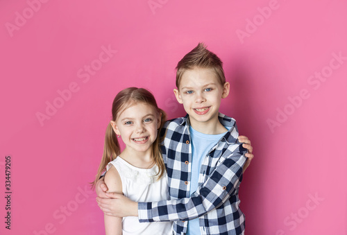 cute children, brother and sister 7-9 years old on a pink background smiling