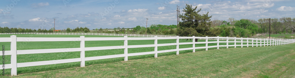 Panoramic long wooden white fence to horizontal line in cloud blue sky at farmland in Ennis, Texas, USA